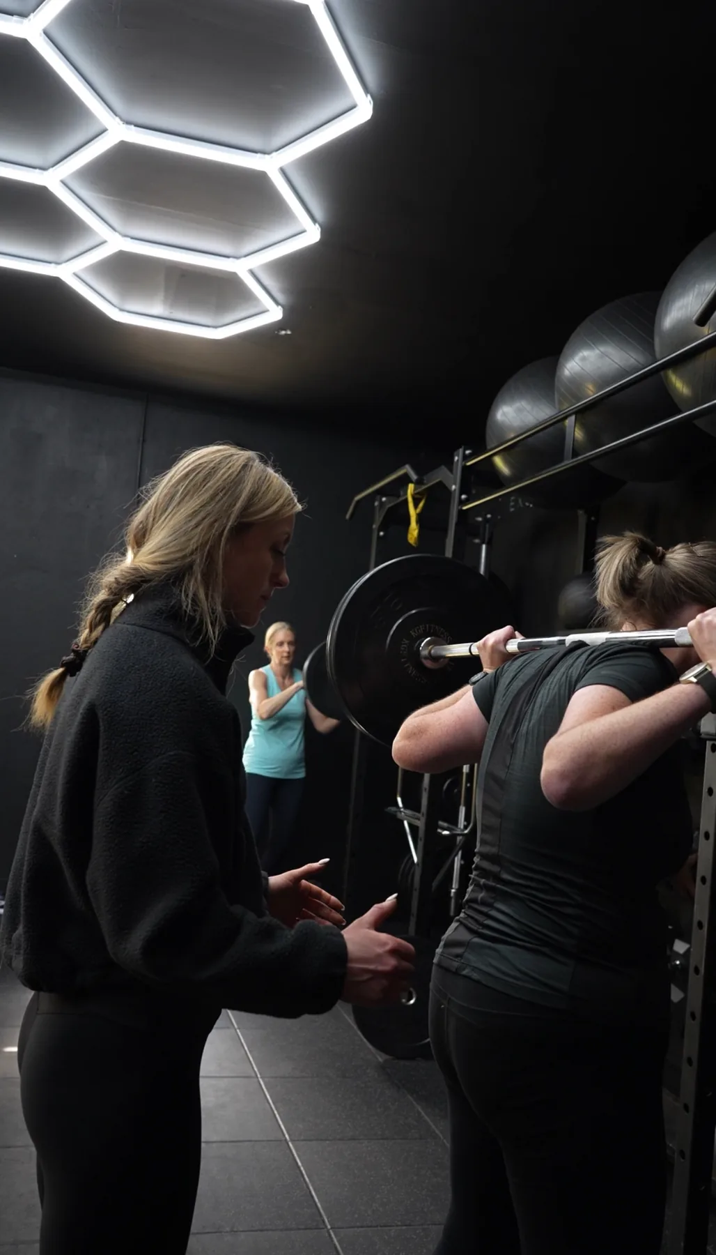 An Excape coach guiding a member through a squat