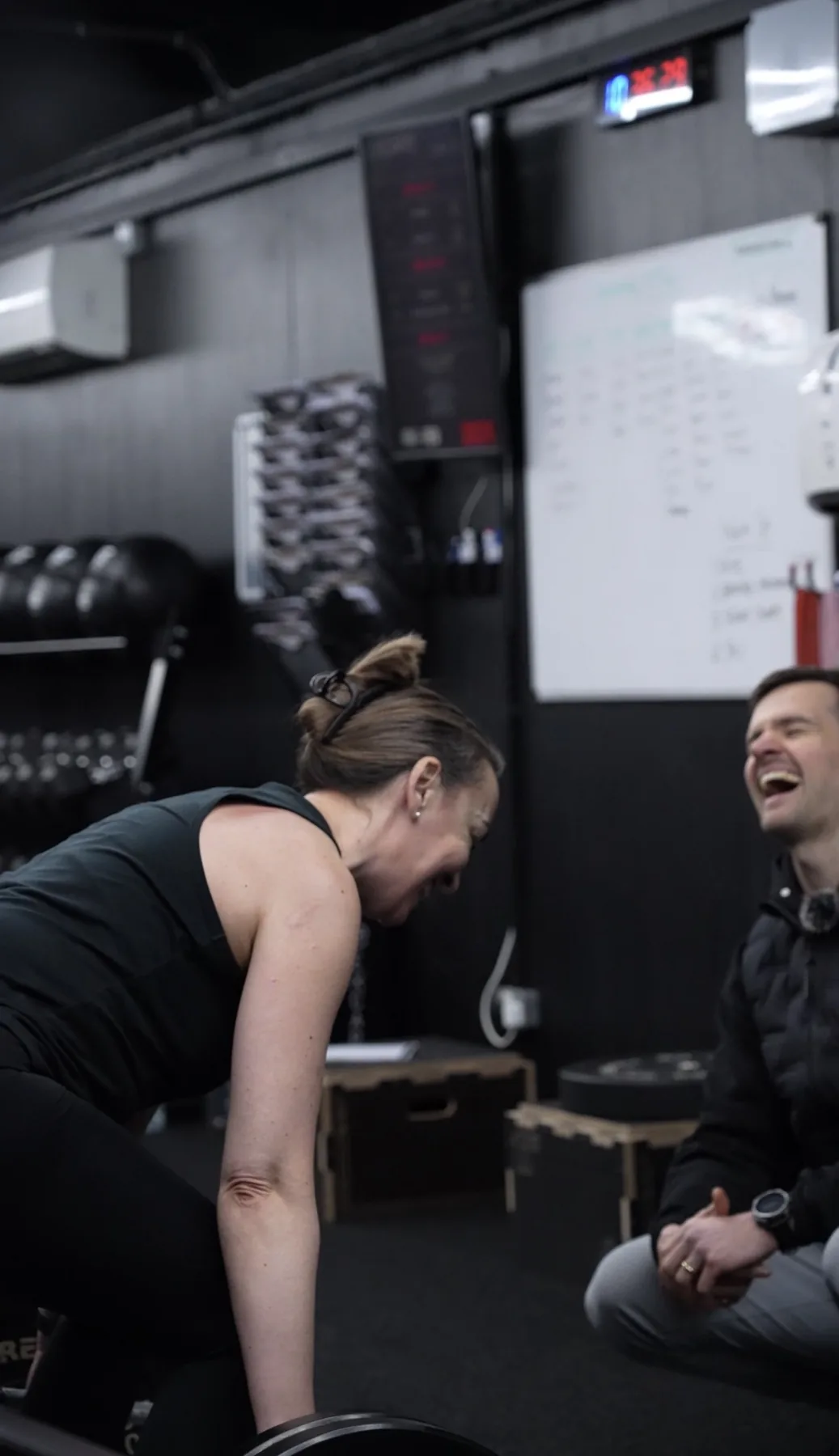 A member and coach sharing a laugh mid-session at Excape